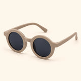 One pair of round sunglasses in the Soft Beige option on a warm beige background.