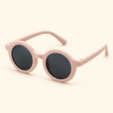 One pair of round sunglasses in the Coral Bloom option on a warm beige background.