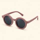One pair of round sunglasses in the Dusty Rose option on a warm beige background.