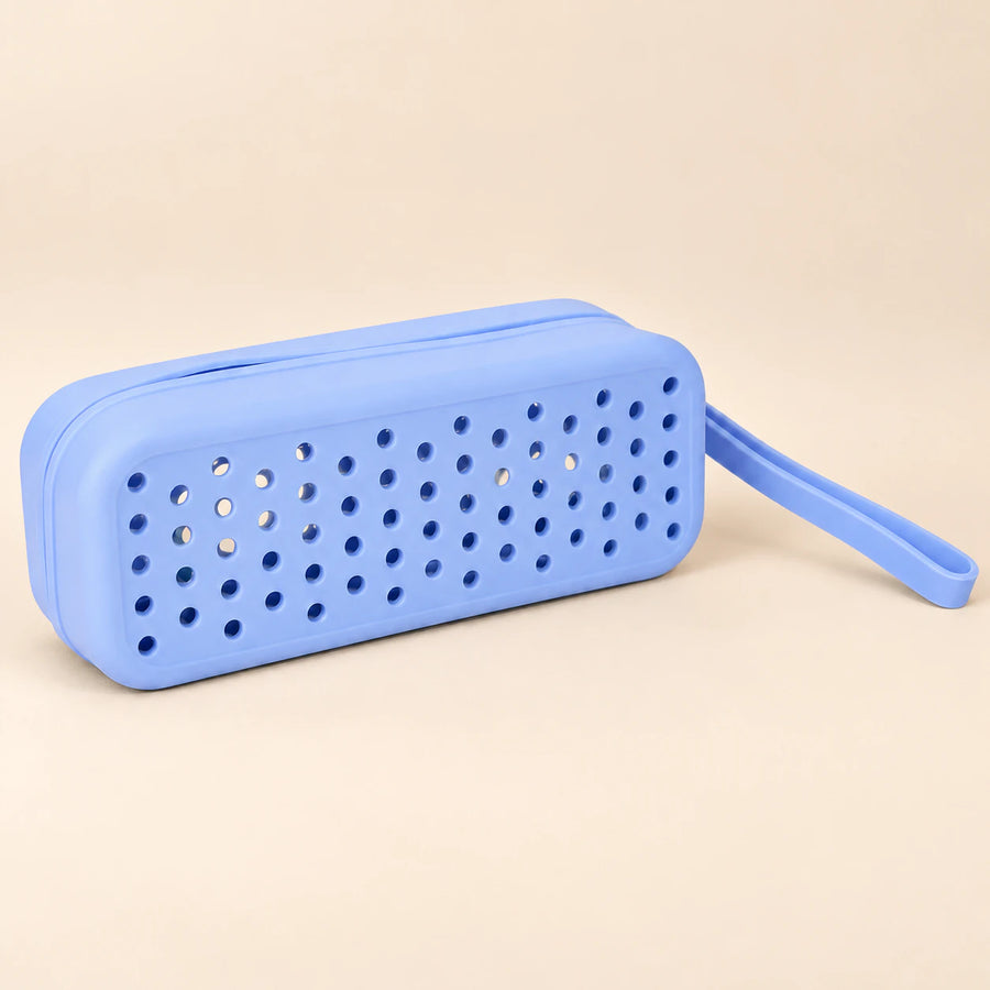 Blue goggle case with ventilation holes and matching carry loop on a smooth warm beige background.