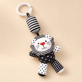 Black and white lion hanging rattle with its clip and patterned cushion on a sunlit beige tabletop.