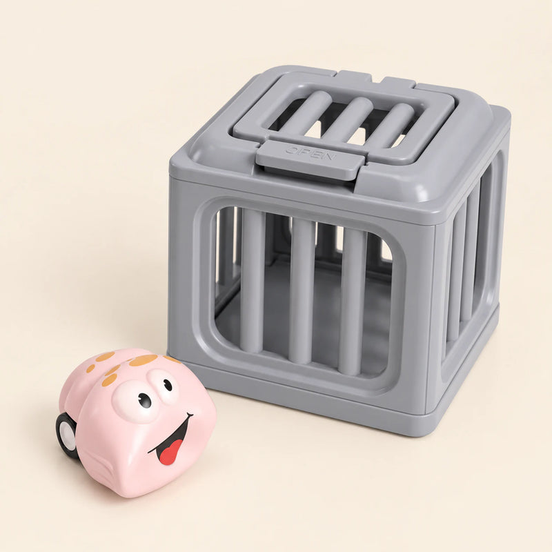 One pale pink ray with golden spots and smiling face toy beside one gray rescue cage on a warm beige background. This is one separate variant choice.