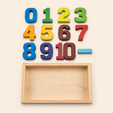 Colourful wooden number blocks and an empty wooden tray on warm beige.