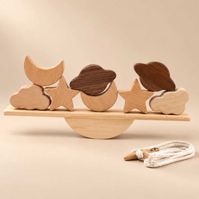 Two moons, two stars, two clouds and two planet-shaped pieces on a straight wooden balance plank, with a semicircular rocker and threading cord.