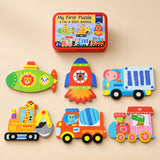 A storage tin and six assembled puzzles showing submarine, rocket, truck, excavator, mixer and train on a sunlit beige table.