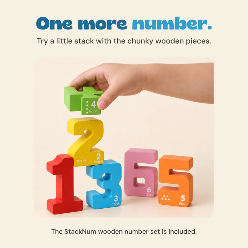 A hand holds a green wooden four above a yellow two, with red one, blue three, pink six and orange five nearby.