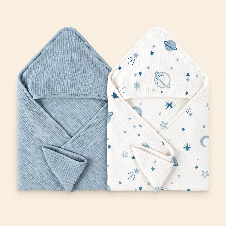 Two hooded towels, one plain sky blue and one white with a space print. Shown on warm beige.
