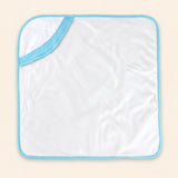 White hooded towel with blue edge binding, laid flat alone on warm beige.