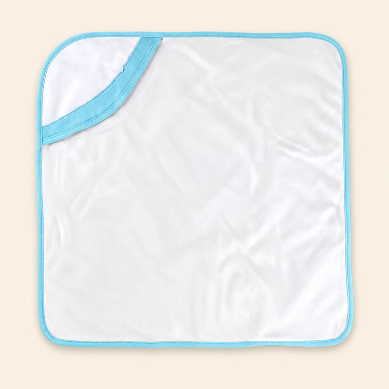 White hooded towel with blue edge binding, laid flat alone on warm beige.
