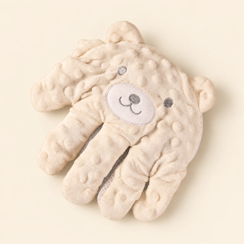 Cream hand-shaped plush pillow with its original embroidered character face and raised-dot fabric, alone on warm beige.