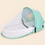 Open mint green tent with a white mesh canopy, padded oval interior and three hanging animal toys on warm beige.