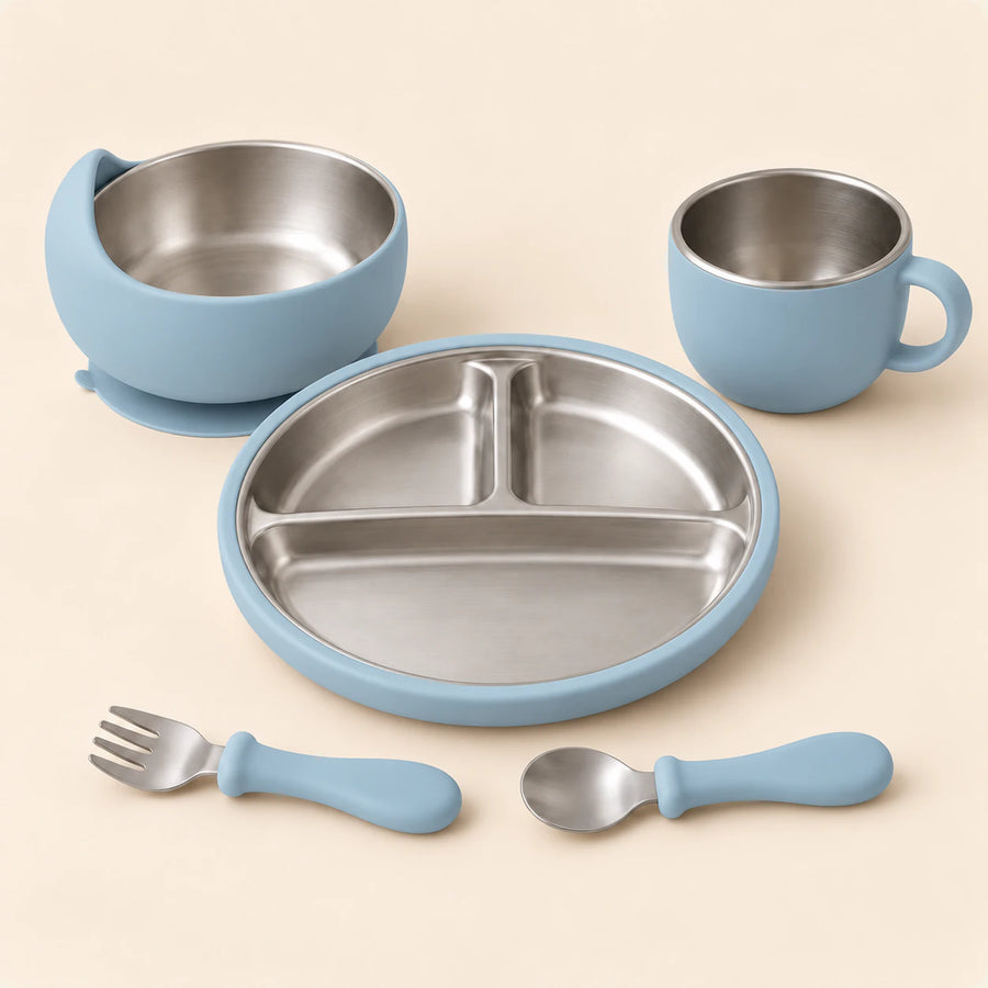 Sky Blue Dine Set with empty three-section stainless steel plate, bowl, single-handled cup, spoon and fork on warm beige.