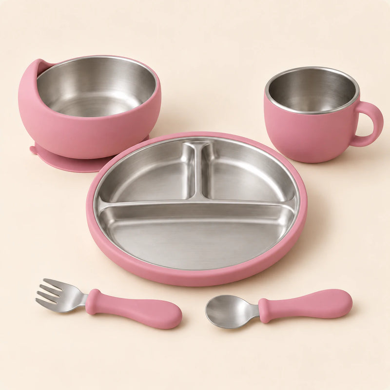 Rose Dine Set with empty three-section stainless steel plate, bowl, single-handled cup, spoon and fork on warm beige.