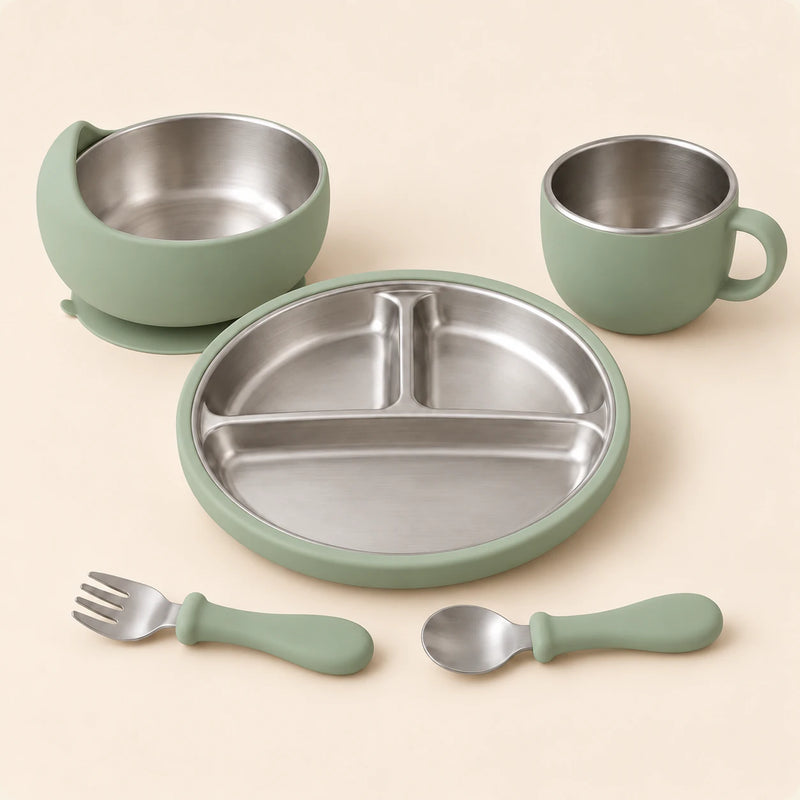 Sage Dine Set with empty three-section stainless steel plate, bowl, single-handled cup, spoon and fork on warm beige.
