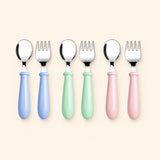 Six utensils arranged as three matching spoon and fork pairs in blue, mint and pink, with metal heads and rounded handles.