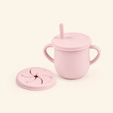 Soft Pink silicone cup with two side handles, fitted straw lid and straw, plus a separate snack lid on warm beige.