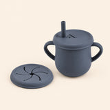 Deep Blue silicone cup with two side handles, fitted straw lid and straw, plus a separate snack lid on warm beige.