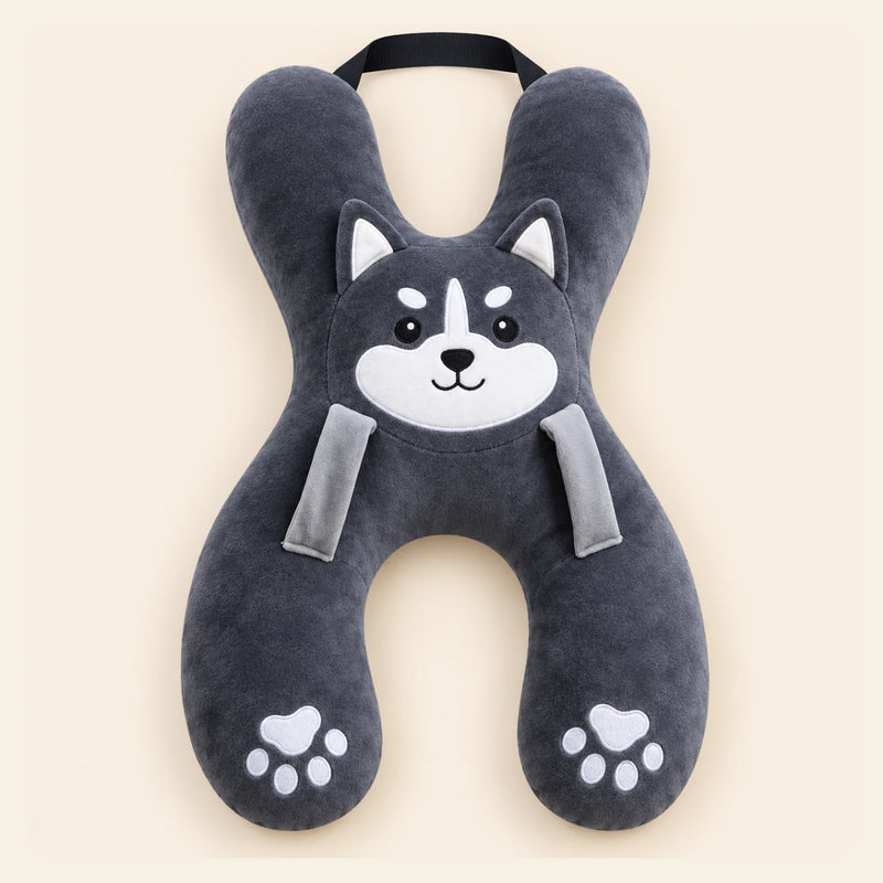 Charcoal Husky travel pillow with its original face, wraparound shape, front loops and upper strap on warm beige.