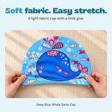 Two hands gently holding the sides of the blue whale fabric swim cap to show its stretch.