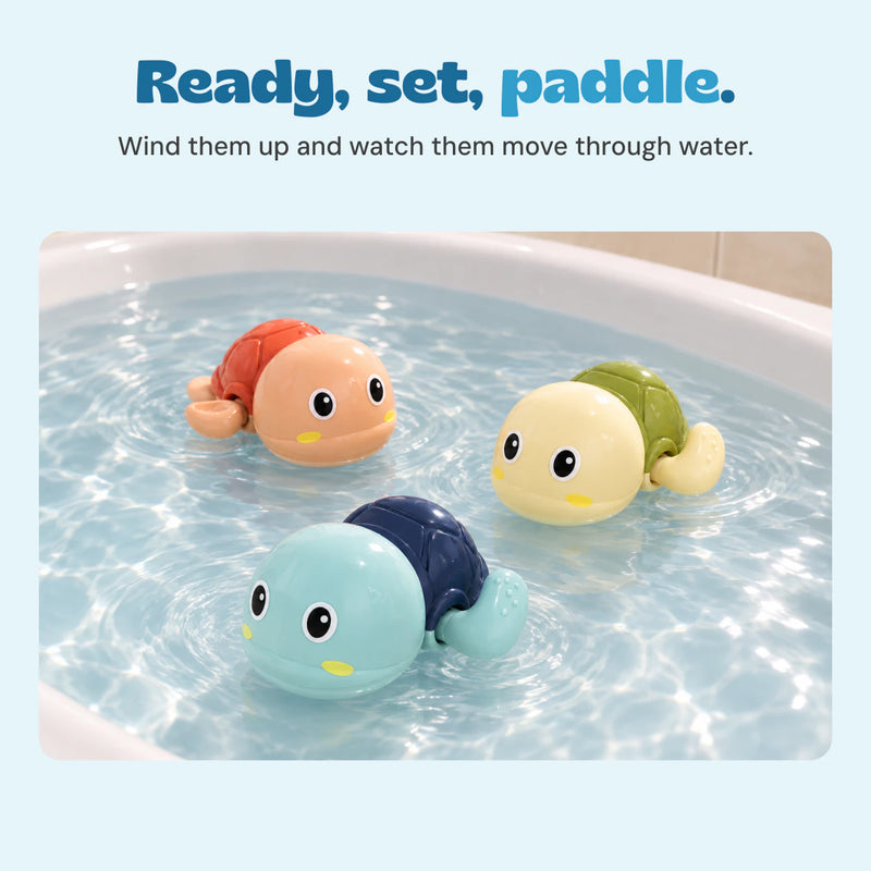 Three colourful wind-up turtles float in clear bath water.