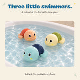 Three plastic wind-up turtles float in shallow bath water.