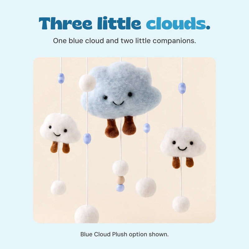 Close-up of the Blue Cloud Plush mobile's large smiling light blue cloud and two small white clouds, with brown dangling legs and white pom poms.
