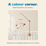 Wooden arm supports the original celestial mobile above an empty white crib in a calm neutral setting. The mobile and crib are not included.