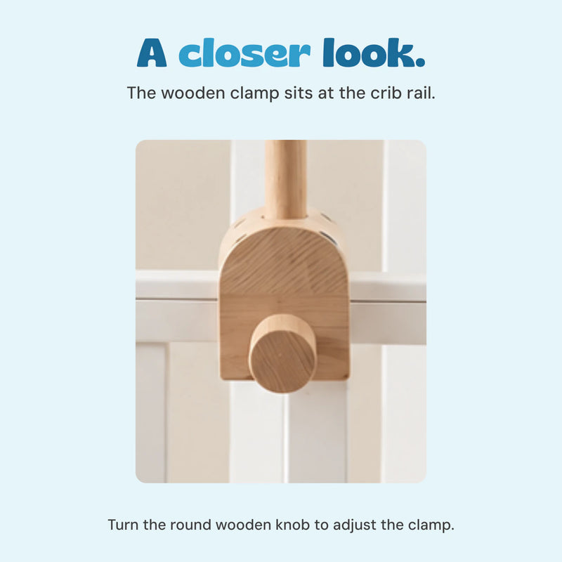 Close view of the wooden clamp and round adjustment knob where the mobile arm meets the crib rail.